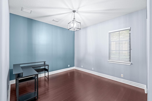 unfurnished room with dark wood-type flooring, a chandelier, and a textured ceiling