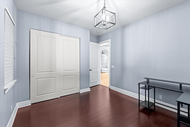 bedroom with dark wood-type flooring, a closet, a textured ceiling, and a notable chandelier