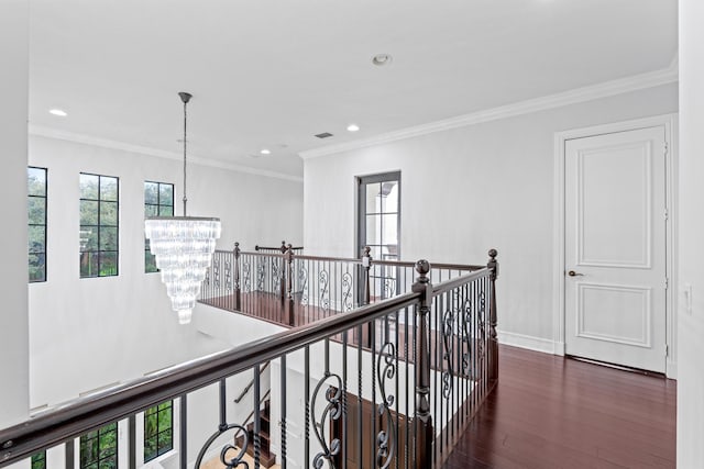 hall with dark wood-type flooring, an inviting chandelier, and crown molding