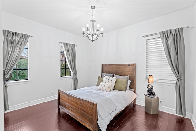 bedroom with multiple windows, dark hardwood / wood-style floors, and an inviting chandelier