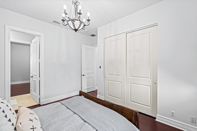 bedroom with an inviting chandelier, hardwood / wood-style flooring, and a closet