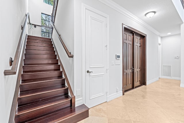 stairs featuring a textured ceiling and crown molding