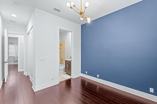 empty room with hardwood / wood-style floors and a notable chandelier