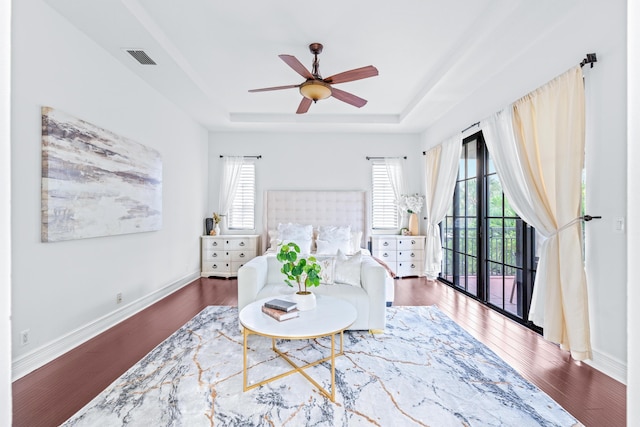 living area featuring hardwood / wood-style flooring, ceiling fan, and a tray ceiling