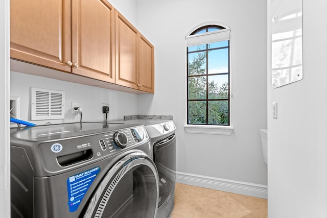 clothes washing area with light tile patterned floors, cabinets, and washing machine and clothes dryer