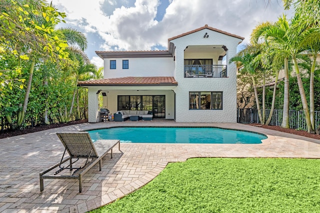 back of house with a balcony, an outdoor living space, and a patio area