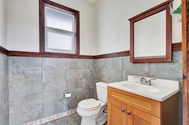 bathroom featuring tile patterned floors, vanity, toilet, and tile walls