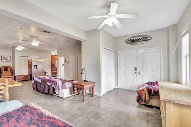 bedroom featuring multiple closets, stainless steel fridge, and ceiling fan