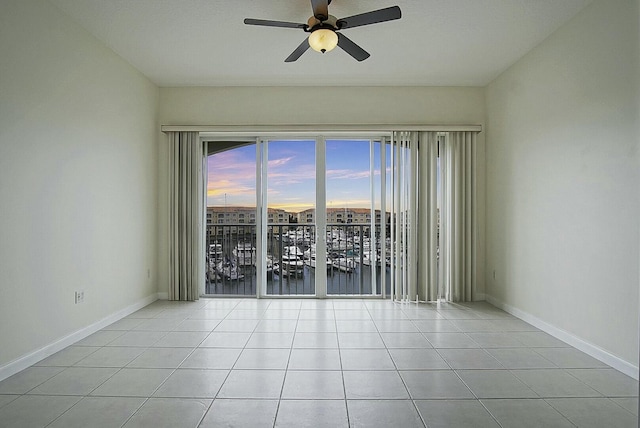 unfurnished room with light tile patterned floors, a ceiling fan, and baseboards