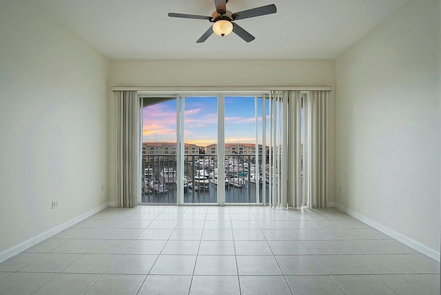 tiled empty room with ceiling fan and a water view