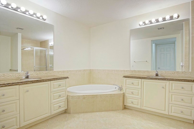 bathroom featuring tile patterned flooring, vanity, a textured ceiling, and separate shower and tub