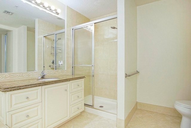 bathroom featuring tile patterned flooring, toilet, a shower with shower door, and a textured ceiling