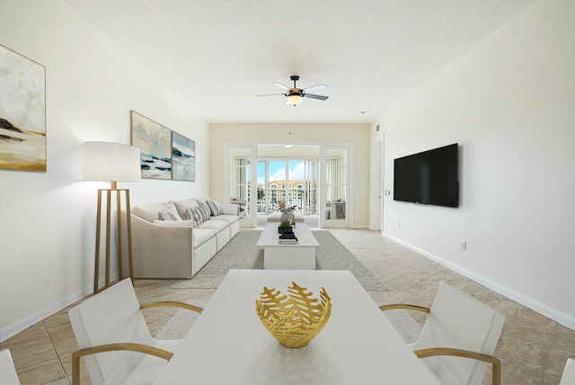 living area featuring ceiling fan, baseboards, a textured ceiling, and light tile patterned flooring