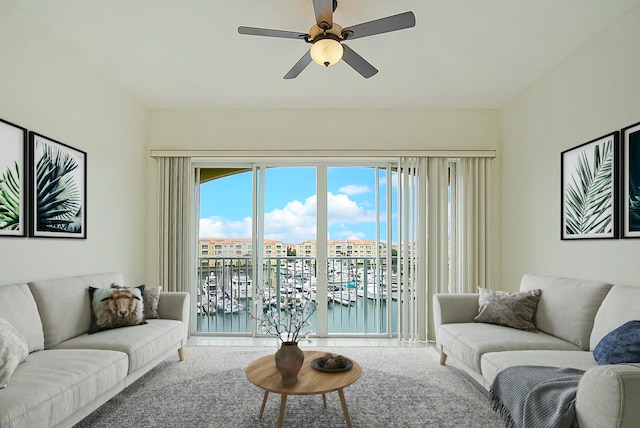 carpeted living room with ceiling fan and a water view