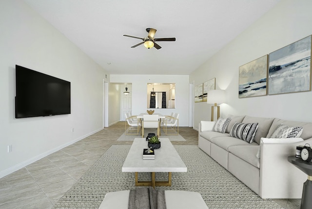 living area featuring baseboards and a ceiling fan