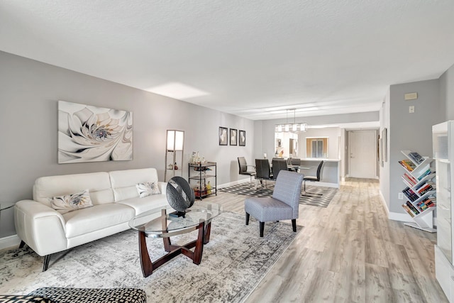 living room featuring an inviting chandelier, light hardwood / wood-style floors, and a textured ceiling