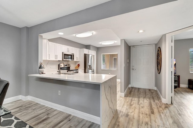 kitchen with white cabinetry, stainless steel appliances, kitchen peninsula, and sink