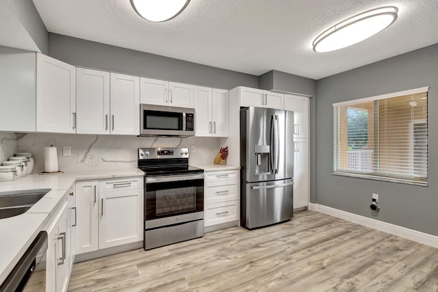 kitchen with white cabinetry, stainless steel appliances, and light hardwood / wood-style floors