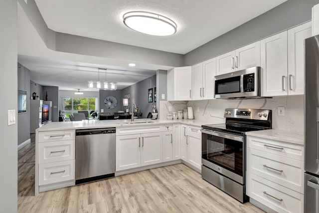 kitchen featuring white cabinetry, sink, kitchen peninsula, and appliances with stainless steel finishes