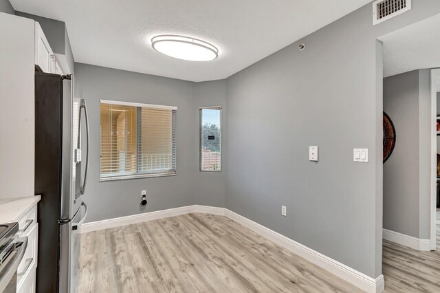 laundry area with a textured ceiling and light wood-type flooring