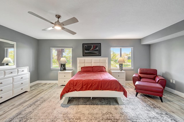 bedroom featuring ceiling fan, a textured ceiling, and light wood-type flooring