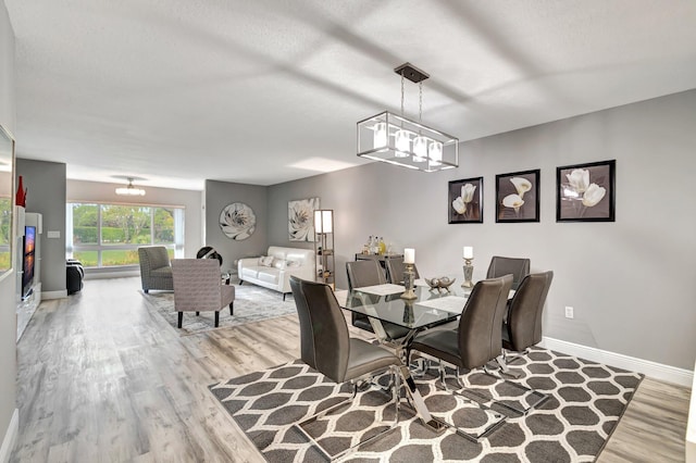 dining area featuring a notable chandelier, light hardwood / wood-style flooring, and a textured ceiling