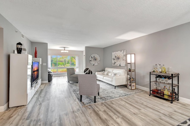 living room featuring light hardwood / wood-style flooring and a textured ceiling