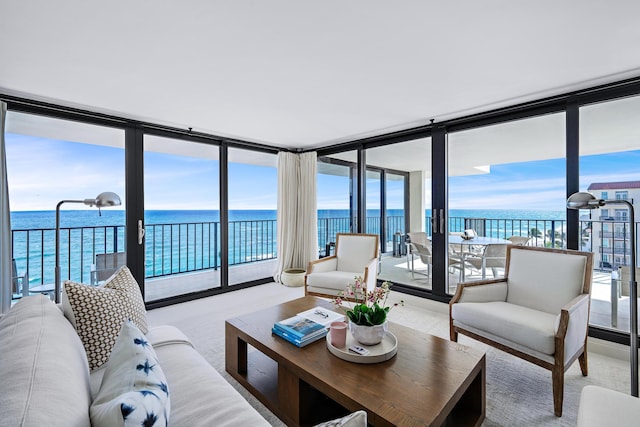 living room featuring expansive windows, a water view, light colored carpet, and a wealth of natural light