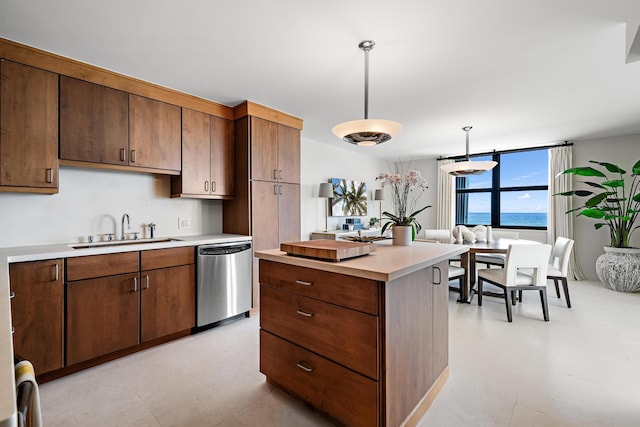 kitchen with a center island, dishwasher, hanging light fixtures, sink, and a water view