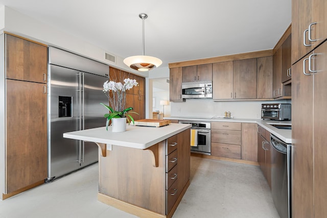 kitchen featuring appliances with stainless steel finishes, a kitchen island, hanging light fixtures, and a breakfast bar area