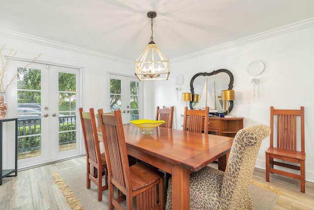 dining room with french doors, light wood-type flooring, an inviting chandelier, and crown molding