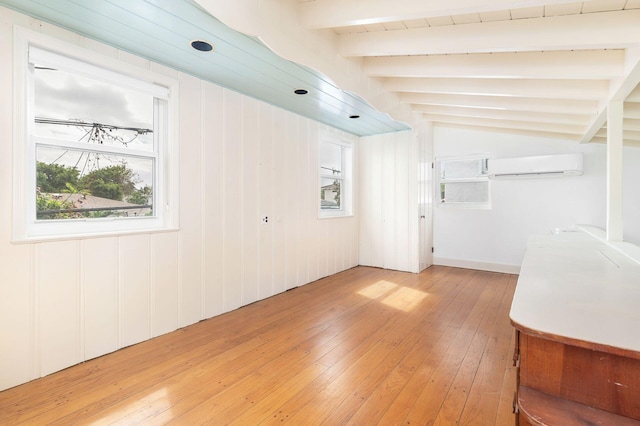 interior space featuring an AC wall unit, vaulted ceiling with beams, wooden walls, and light hardwood / wood-style flooring