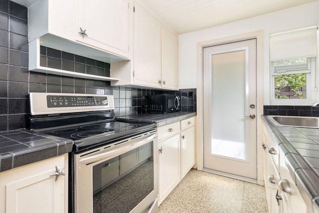 kitchen with stainless steel electric range, sink, tasteful backsplash, tile counters, and white cabinetry