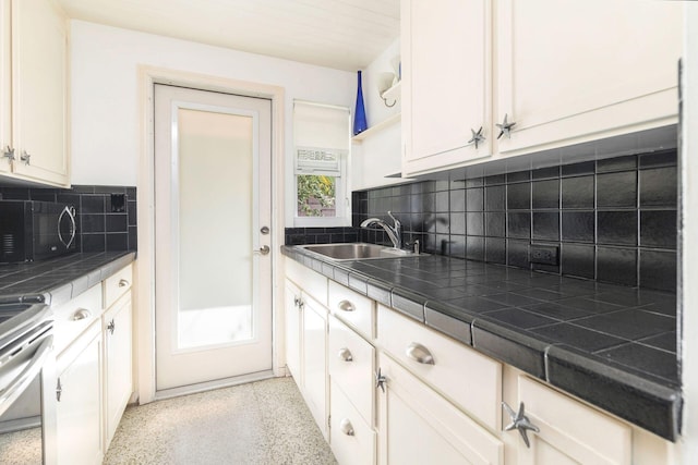 kitchen featuring tile counters, stainless steel range oven, decorative backsplash, and sink