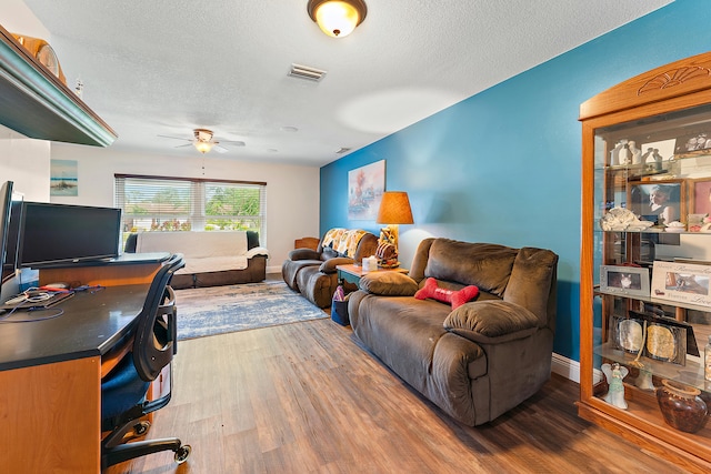 living room featuring ceiling fan, a textured ceiling, and hardwood / wood-style flooring