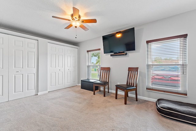 living area with ceiling fan and light colored carpet