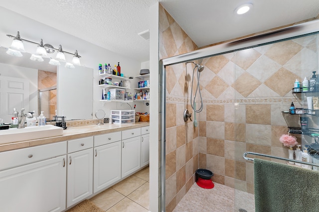 bathroom with a shower with shower door, vanity, tile patterned floors, and a textured ceiling