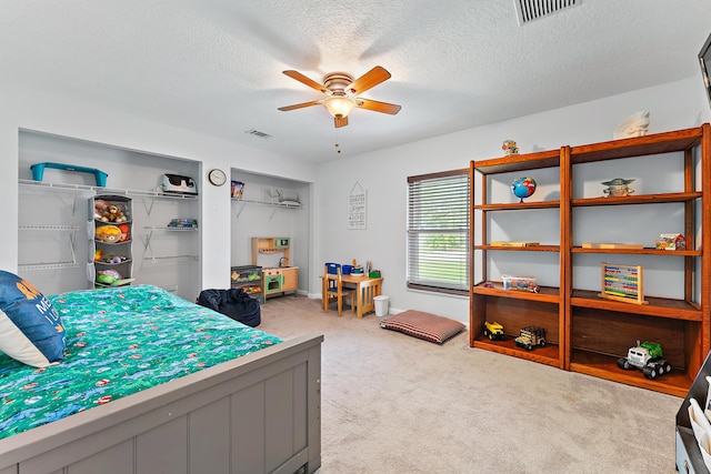 bedroom with a textured ceiling, ceiling fan, carpet flooring, and a closet