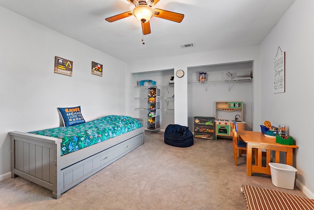 carpeted bedroom with ceiling fan and a textured ceiling