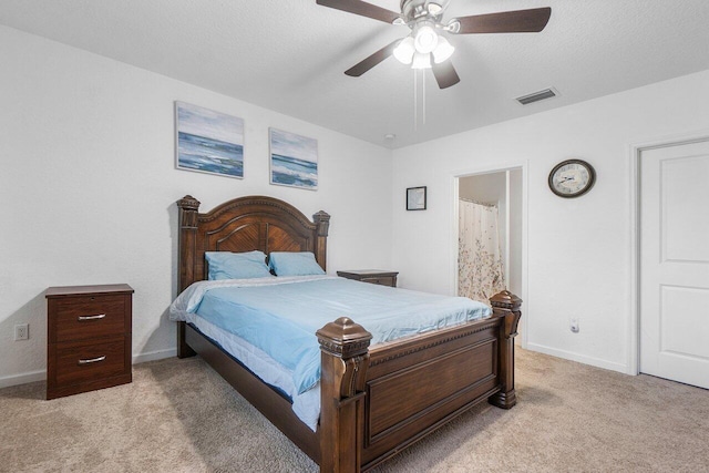 bedroom featuring a textured ceiling, ceiling fan, ensuite bathroom, and light carpet