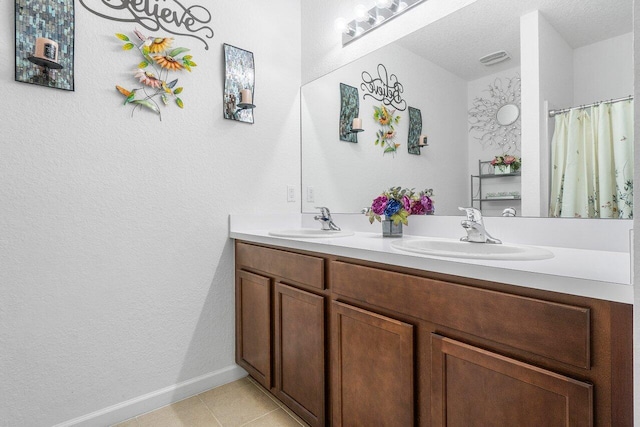 bathroom with vanity, a textured ceiling, and tile patterned flooring