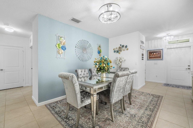 tiled dining room with a notable chandelier and a textured ceiling