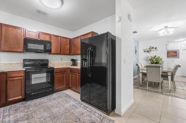 kitchen with light tile patterned floors, a textured ceiling, and black appliances