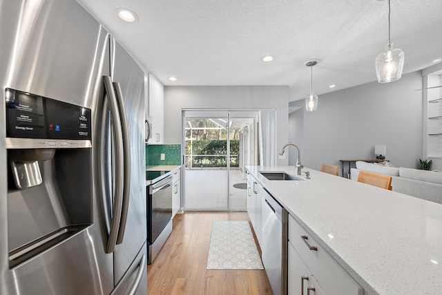 kitchen with white cabinets, light wood-style floors, appliances with stainless steel finishes, and a sink