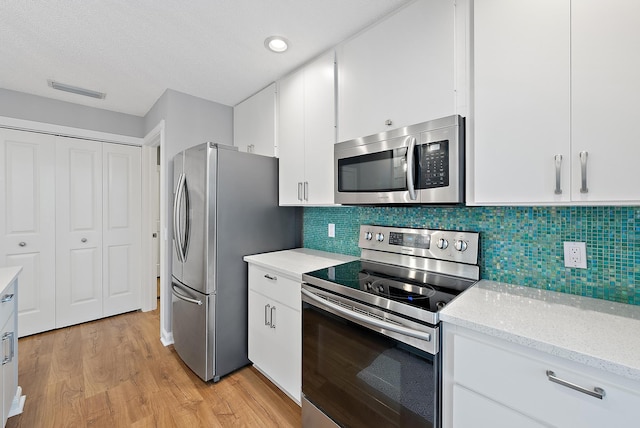 kitchen featuring light stone counters, stainless steel appliances, light wood-style floors, and white cabinetry