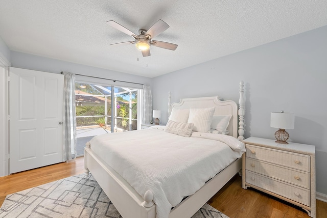 bedroom with access to exterior, a textured ceiling, a ceiling fan, and wood finished floors