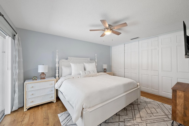 bedroom featuring visible vents, light wood-style floors, a closet, a textured ceiling, and a ceiling fan