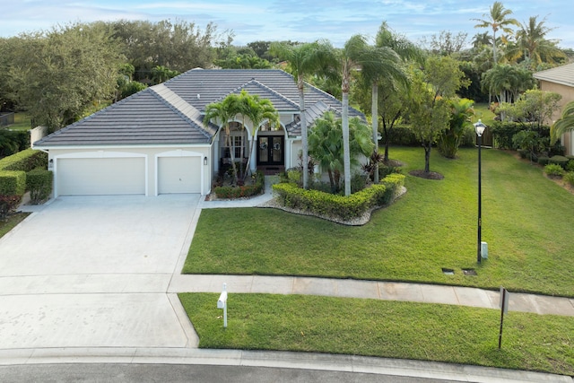 mediterranean / spanish-style home with a garage, a front yard, and french doors