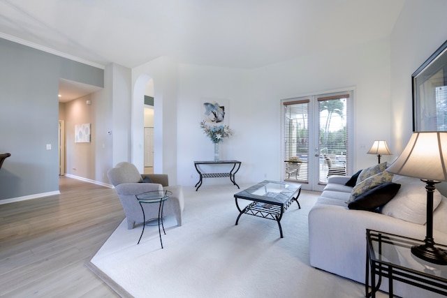 living room with french doors, ornamental molding, and light wood-type flooring