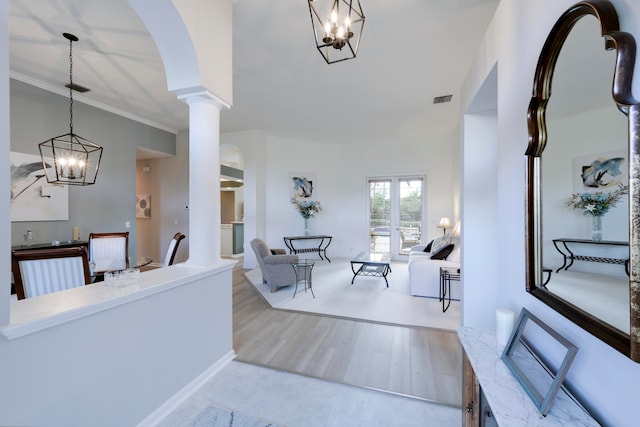 foyer featuring light wood-type flooring, crown molding, and ornate columns